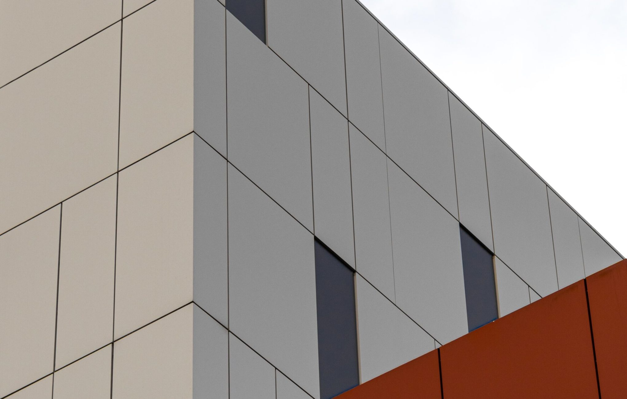 A low angle shot of a modern white and orange building under the bright sky